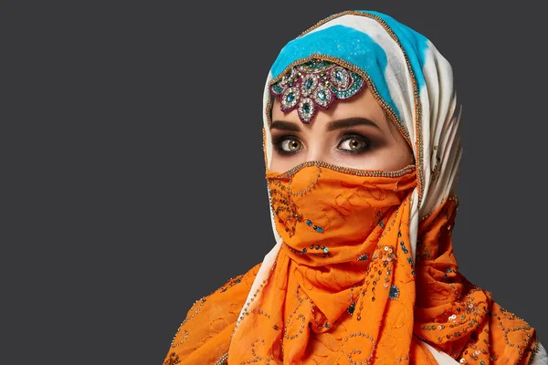 Studio shot van een chrming vrouw het dragen van de kleurrijke hijab versierd met pailletten en sieraden. Arabische stijl. — Stockfoto