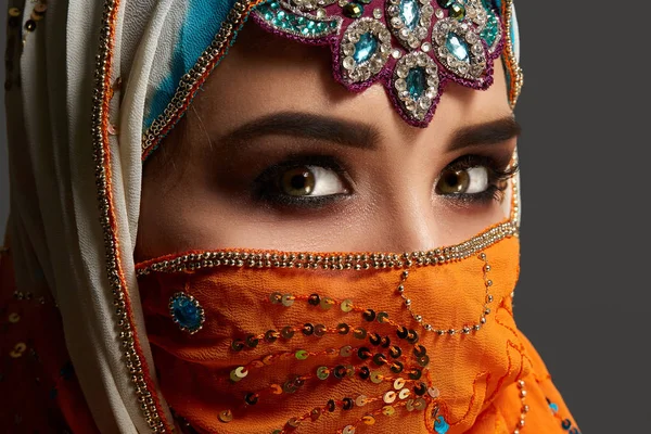 Ένα στούντιο σφηνάκι από ένα θηλυκό που φοράει το πολύχρωμο χιτζάμπ διακοσμημένο με πούλιες και κοσμήματα. Αραβικό στυλ. — Φωτογραφία Αρχείου