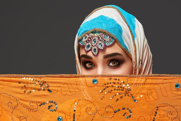 Studio shot van een chrming vrouw het dragen van de kleurrijke hijab versierd met pailletten en sieraden. Arabische stijl. — Stockfoto