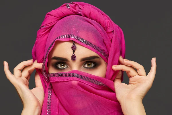 Close-up de uma jovem mulher encantadora vestindo o hijab rosa decorado com lantejoulas e jóias. Estilo árabe . — Fotografia de Stock