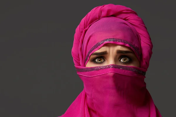 Close-up shot of a young charming woman wearing the pink hijab decorated with sequins. Arabic style.