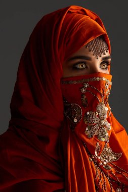 Payetler ve takılar ile süslenmiş terracotta hijab giyen genç bir büyüleyici kadın stüdyo çekim. Arap tarzı.