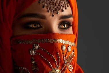 Payetler ve takılar ile süslenmiş terracotta hijab giyen genç bir büyüleyici kadın stüdyo çekim. Arap tarzı.