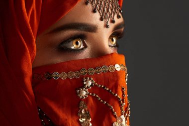 Payetler ve takılar ile süslenmiş terracotta hijab giyen genç bir büyüleyici kadın stüdyo çekim. Arap tarzı.