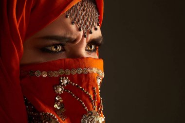 Payetler ve takılar ile süslenmiş terracotta hijab giyen genç bir büyüleyici kadın stüdyo çekim. Arap tarzı.