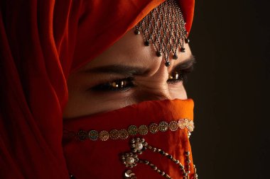 Payetler ve takılar ile süslenmiş terracotta hijab giyen genç bir büyüleyici kadın stüdyo çekim. Arap tarzı.