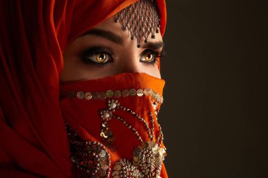 Payetler ve takılar ile süslenmiş terracotta hijab giyen genç bir büyüleyici kadın stüdyo çekim. Arap tarzı.