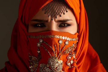 Payetler ve takılar ile süslenmiş terracotta hijab giyen genç bir büyüleyici kadın stüdyo çekim. Arap tarzı.