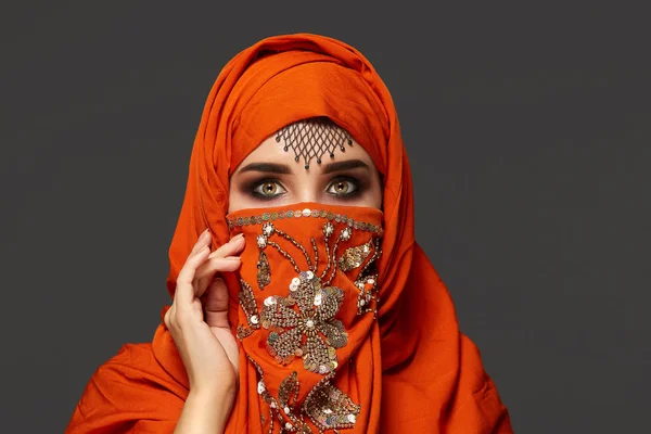 Studiová střela mladé okouzlující ženy s terakotovou hidžábu ozdobená sekernami a šperky. Arabský styl. — Stock fotografie