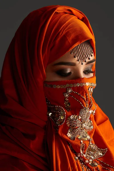 Foto de estudio de una joven encantadora mujer con el hiyab de terracota decorado con lentejuelas y joyas. Estilo árabe . —  Fotos de Stock