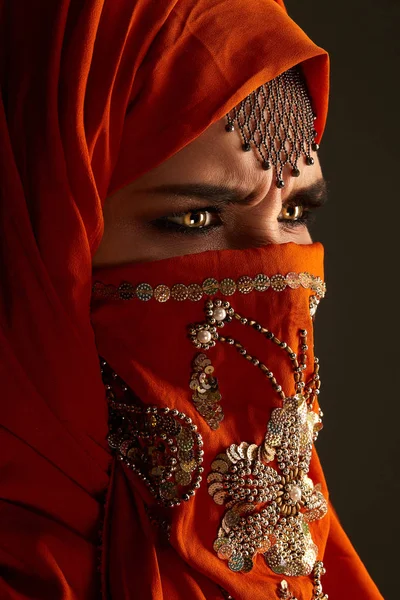 Studio shot of a young charming woman wearing the terracotta hijab decorated with sequins and jewelry. Arabic style. — Stock Photo, Image