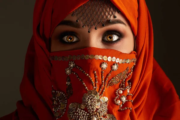 Studio skott av en ung charmig kvinna klädd i terrakotta hijab dekorerad med paljetter och smycken. Arabisk stil. — Stockfoto