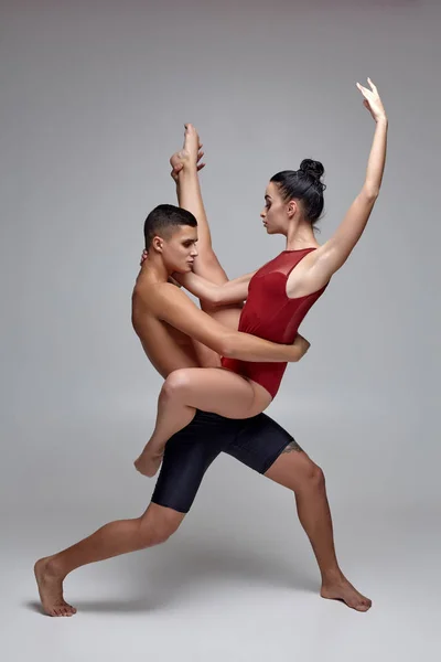 O casal de um atlético bailarinos modernos estão posando contra um fundo de estúdio cinza . — Fotografia de Stock