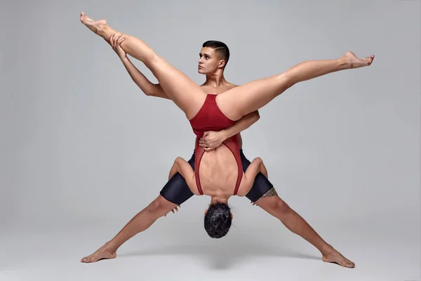 Το ζευγάρι των αθλητικών σύγχρονων χορευτών μπαλέτου ποζάρει σε ένα γκρίζο φόντο στούντιο. — Φωτογραφία Αρχείου