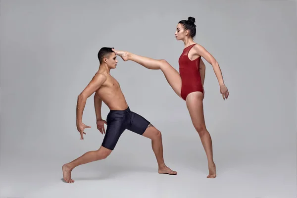 Το ζευγάρι των αθλητικών σύγχρονων χορευτών μπαλέτου ποζάρει σε ένα γκρίζο φόντο στούντιο. — Φωτογραφία Αρχείου