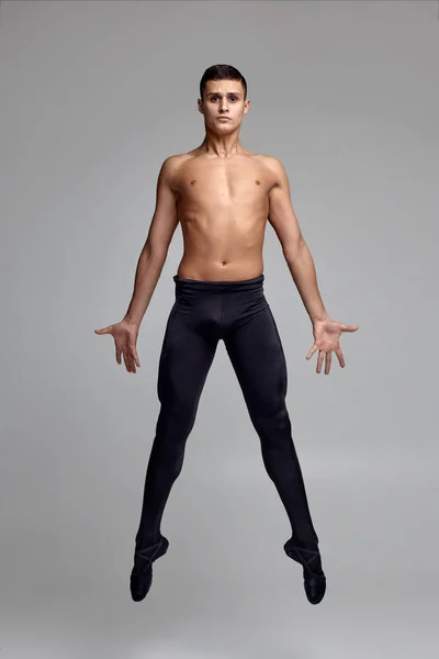 운동 남자 발레 댄서의 사진, 검은 스타킹과 뾰족한 옷을 입고, 스튜디오에서 회색 배경에 댄스 요소를 만들기. — 스톡 사진