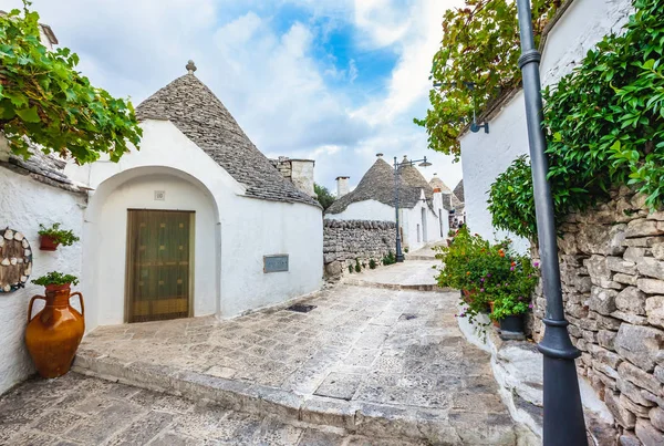 Gyönyörű Alberobello város Trulli házakkal a zöld növények és virágok között, Apulia régió, Dél-Olaszország. — Stock Fotó