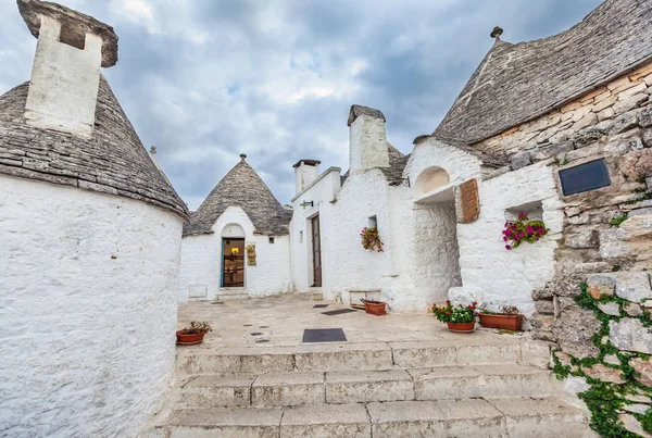 Gyönyörű Alberobello város Trulli házakkal a zöld növények és virágok között, Apulia régió, Dél-Olaszország. — Stock Fotó