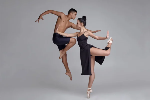 Due ballerini di danza moderna atletica stanno posando su uno sfondo grigio da studio . — Foto Stock