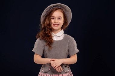 Siyah bir arka plan üzerinde poz uzun, kıvırcık saçlı güzel bir küçük çocuk Stüdyo çekim.