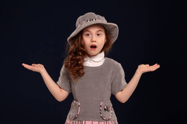 Siyah bir arka plan üzerinde poz uzun, kıvırcık saçlı güzel bir küçük çocuk Stüdyo çekim.