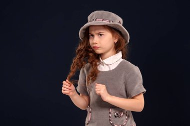 Siyah bir arka plan üzerinde poz uzun, kıvırcık saçlı güzel bir küçük çocuk Stüdyo çekim.