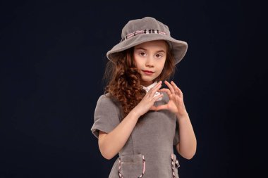 Siyah bir arka plan üzerinde poz uzun, kıvırcık saçlı güzel bir küçük çocuk Stüdyo çekim.