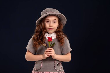 Siyah bir arka plan üzerinde poz uzun, kıvırcık saçlı güzel bir küçük çocuk Stüdyo çekim.