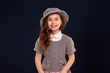 Siyah bir arka plan üzerinde poz uzun, kıvırcık saçlı güzel bir küçük çocuk Stüdyo çekim.