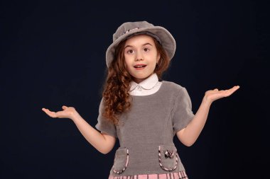 Siyah bir arka plan üzerinde poz uzun, kıvırcık saçlı güzel bir küçük çocuk Stüdyo çekim.