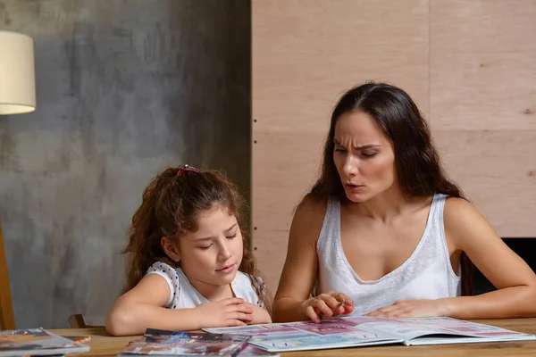 Portrait d'une mère aidant sa petite fille douce et mignonne à faire ses devoirs à l'intérieur. Famille heureuse . — Photo