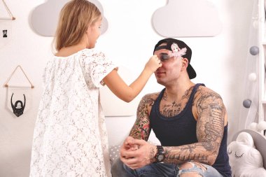 Komik zaman Tattoed baba bir kap ve çocuğu evde oynuyor. Sevimli kız onun yatak odasında babasına makyaj yapıyor. Aile tatili birlikteliği