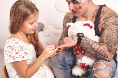 Komik zaman Tattoed baba bir kap ve çocuğu evde oynuyor. Sevimli kız onun yatak odasında babasına makyaj yapıyor. Aile tatili birlikteliği