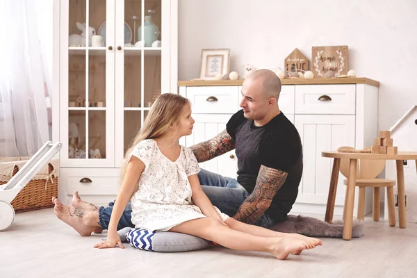 Adorable hija vistiendo un vestido blanco con su padre cariñoso en una habitación de niños modernos con muebles de madera. Familia feliz . —  Fotos de Stock