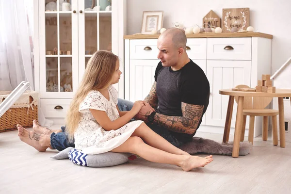 Rozkošná dcera nosí v bílých šatech svůj milující otec v moderním dětním pokoji, kde je dřevěný nábytek. Šťastná rodina. — Stock fotografie