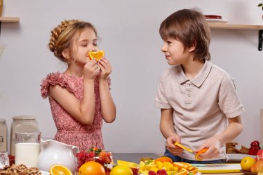 Sevimli çocuklar üzerinde raflar ile beyaz bir duvara karşı bir mutfakta birlikte yemek.