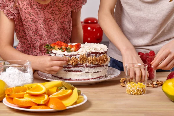 Kis barátok készülnek A Cake együtt A konyha ellen, A fehér fal polcok rajta. — Stock Fotó