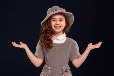 Siyah bir arka plan üzerinde poz uzun, kıvırcık saçlı güzel bir küçük çocuk Stüdyo çekim.