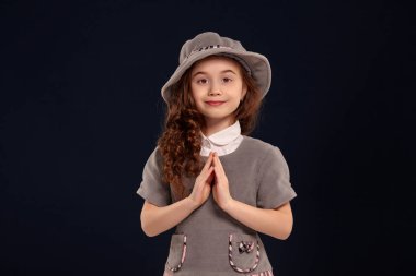 Siyah bir arka plan üzerinde poz uzun, kıvırcık saçlı güzel bir küçük çocuk Stüdyo çekim.