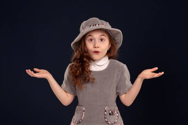 Siyah bir arka plan üzerinde poz uzun, kıvırcık saçlı güzel bir küçük çocuk Stüdyo çekim.