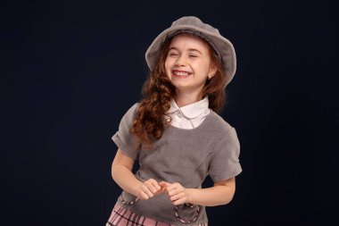 Siyah bir arka plan üzerinde poz uzun, kıvırcık saçlı güzel bir küçük çocuk Stüdyo çekim.