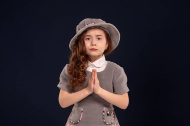 Siyah bir arka plan üzerinde poz uzun, kıvırcık saçlı güzel bir küçük çocuk Stüdyo çekim.