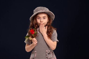 Siyah bir arka plan üzerinde poz uzun, kıvırcık saçlı güzel bir küçük çocuk Stüdyo çekim.