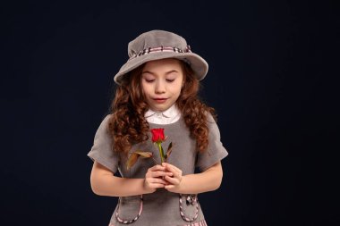 Siyah bir arka plan üzerinde poz uzun, kıvırcık saçlı güzel bir küçük çocuk Stüdyo çekim.