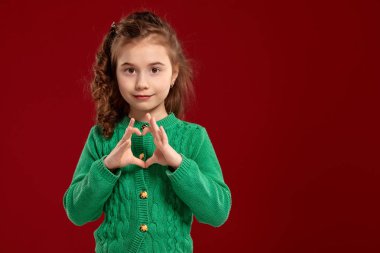 Kırmızı bir arka plan aleyhine poz uzun, kıvırcık saçlı küçük bir esmer kız Portresi.