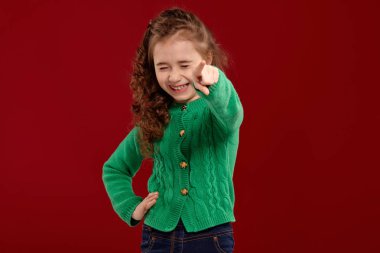 Kırmızı bir arka plan aleyhine poz uzun, kıvırcık saçlı küçük bir esmer kız Portresi.