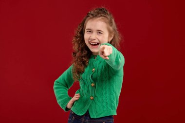 Kırmızı bir arka plan aleyhine poz uzun, kıvırcık saçlı küçük bir esmer kız Portresi.