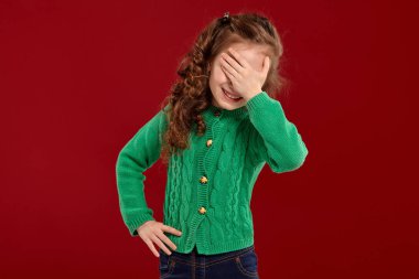 Kırmızı bir arka plan aleyhine poz uzun, kıvırcık saçlı küçük bir esmer kız Portresi.