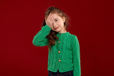 Kırmızı bir arka plan aleyhine poz uzun, kıvırcık saçlı küçük bir esmer kız Portresi.