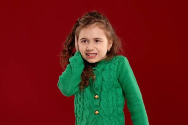 Kırmızı bir arka plan aleyhine poz uzun, kıvırcık saçlı küçük bir esmer kız Portresi.